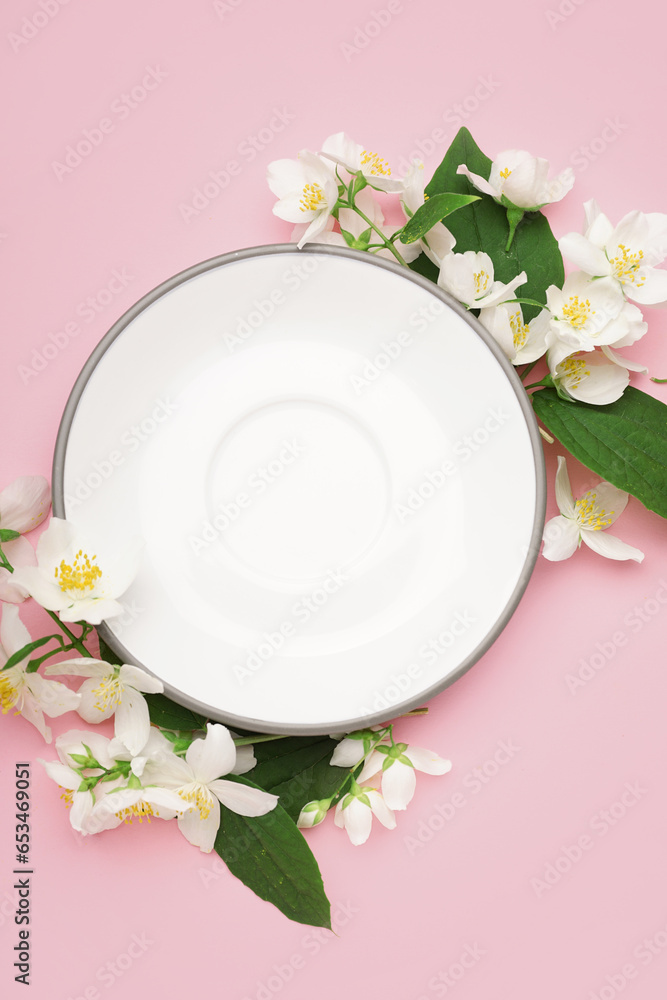 Composition with plate and beautiful jasmine flowers on pink background