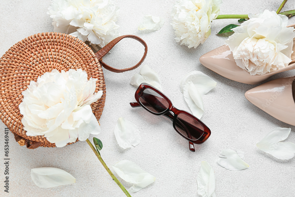 Composition with female sunglasses, bag, high heels and beautiful peony flowers on light background