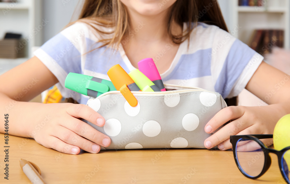 Little girl with pencil case at table, closeup