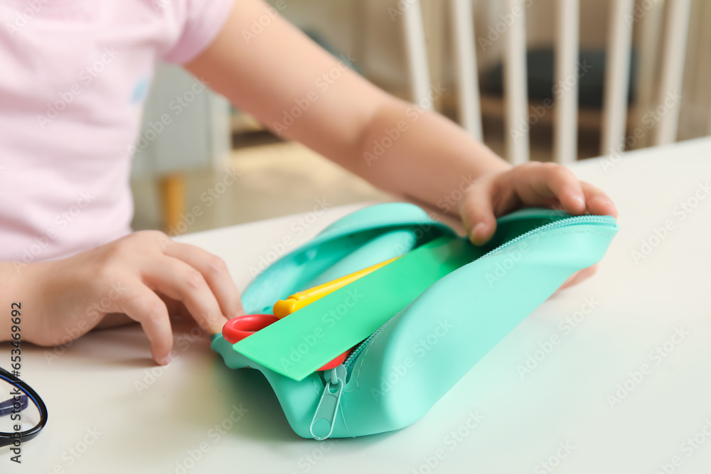 Little girl with pencil case at table, closeup