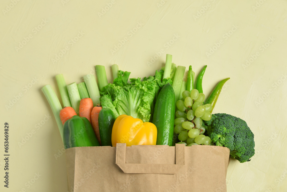 Paper bag with fresh vegetables and fruits on beige background