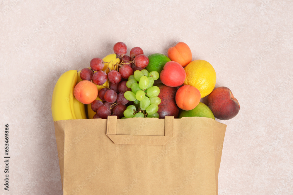 Paper bag with fresh fruits on grey background