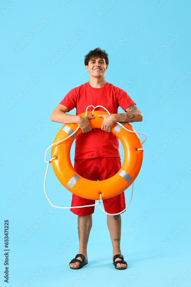 Male lifeguard with ring buoy on blue background