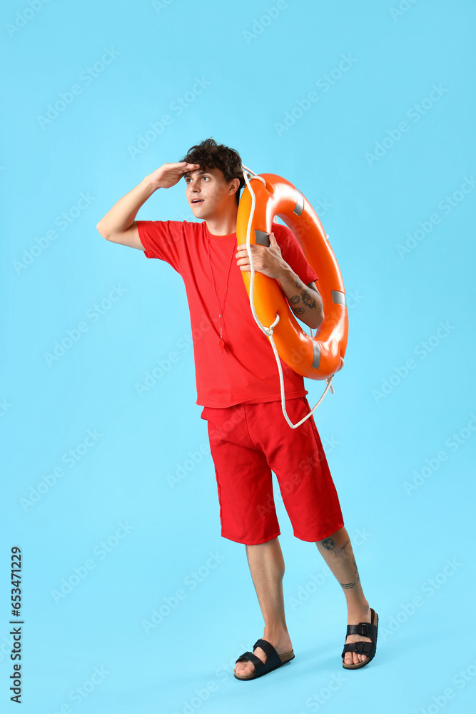 Male lifeguard with ring buoy on blue background