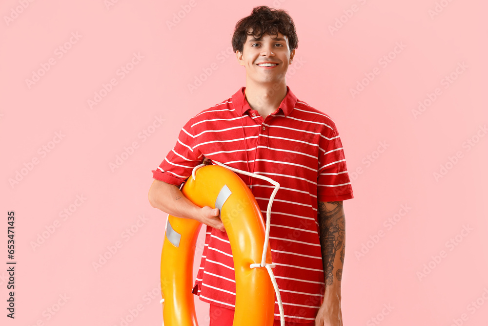 Male lifeguard with ring buoy on pink background