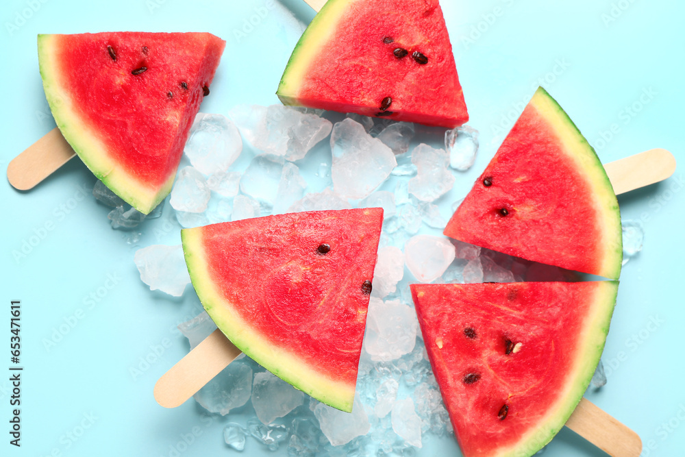 Sweet watermelon sticks and ice cubes on blue background