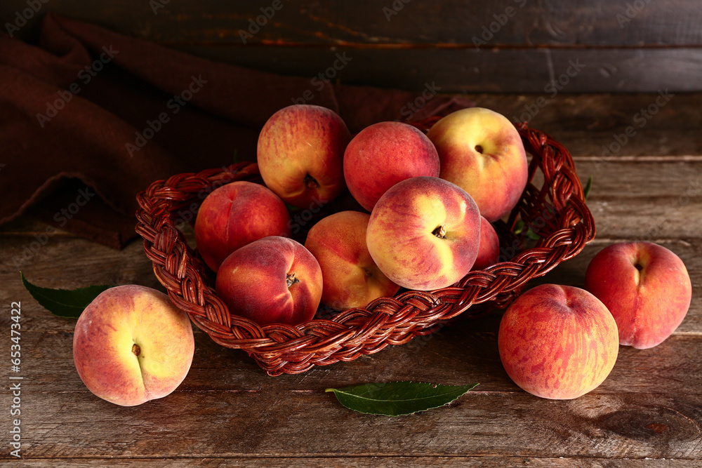 Wicker basket with sweet peaches on wooden background