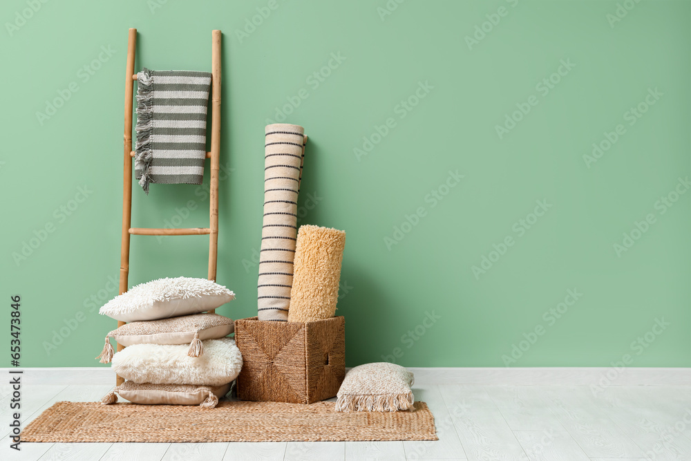 Carpets, cushions and wicker rug near green wall