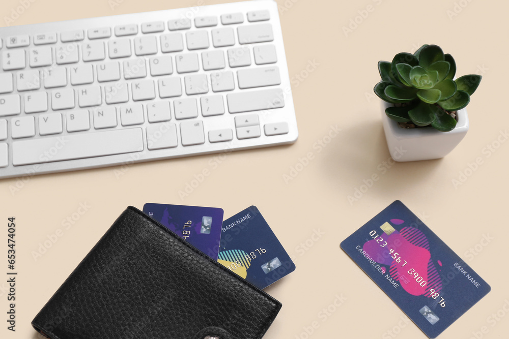 Keyboard with wallet and credit cards on beige background