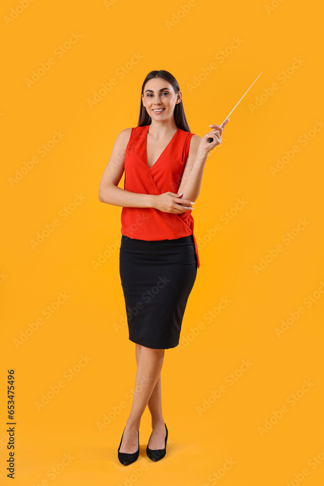 Young female teacher with pointer on yellow background