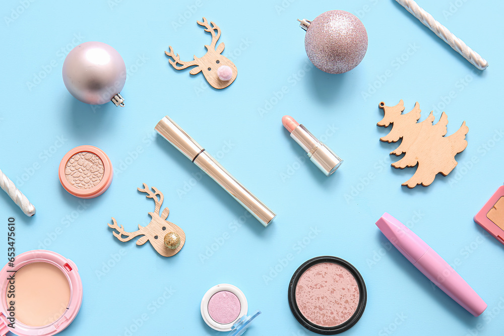 Composition with decorative cosmetics and Christmas decor on blue background