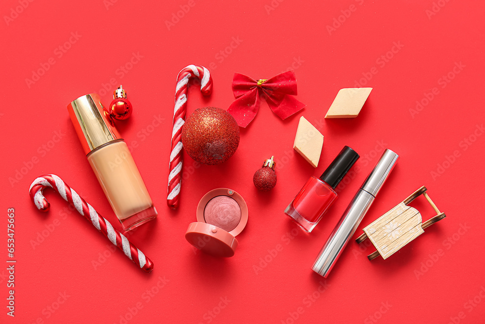 Composition with decorative cosmetics and Christmas decor on red background