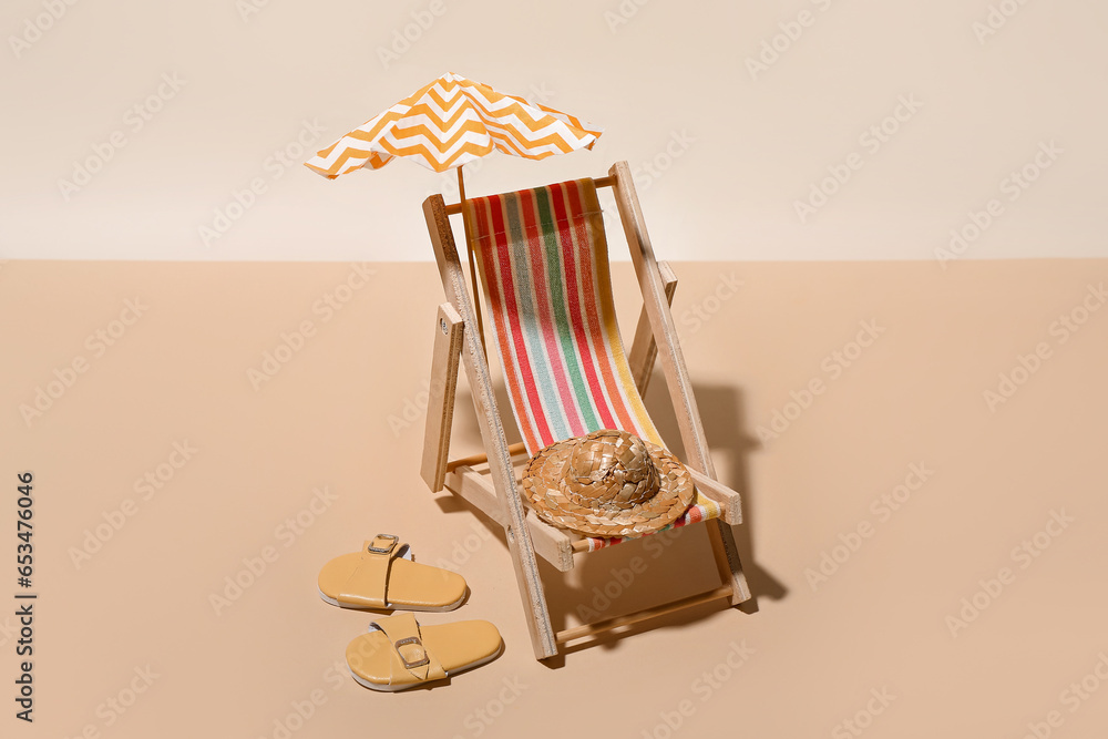 Creative summer composition with mini umbrella, deckchair and beach accessories on color background