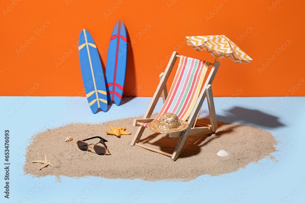 Creative summer composition with mini umbrella, deckchair and beach accessories on color background