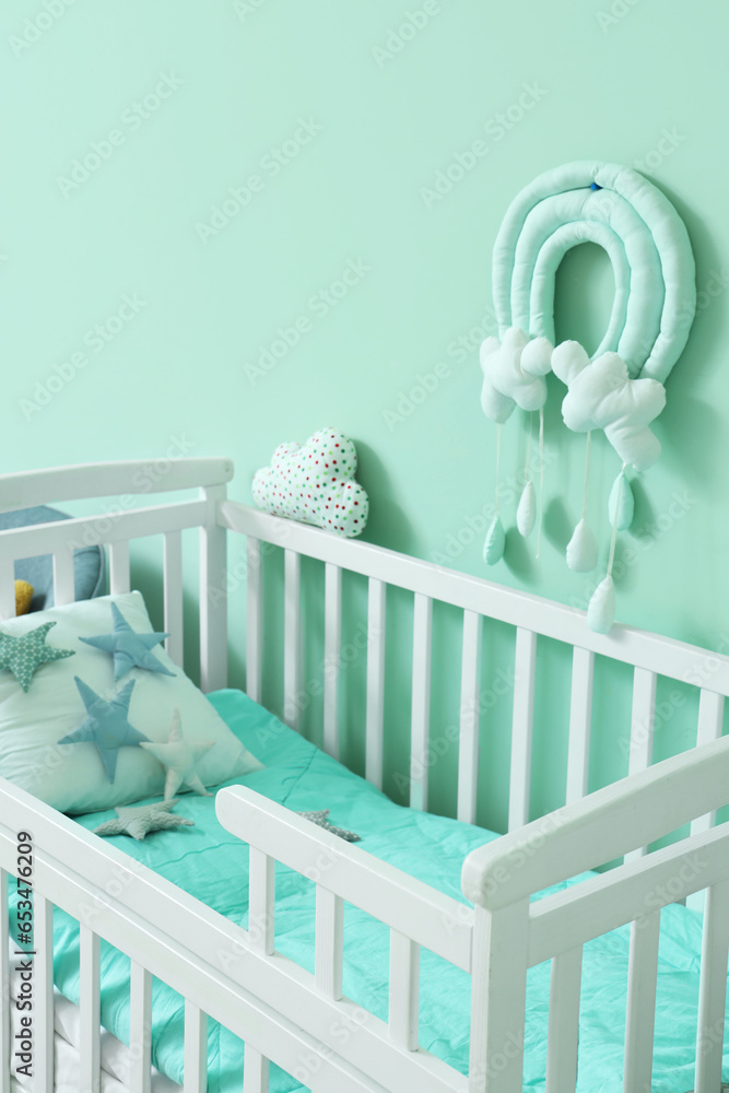 Crib with star pillows near turquoise wall in childrens room