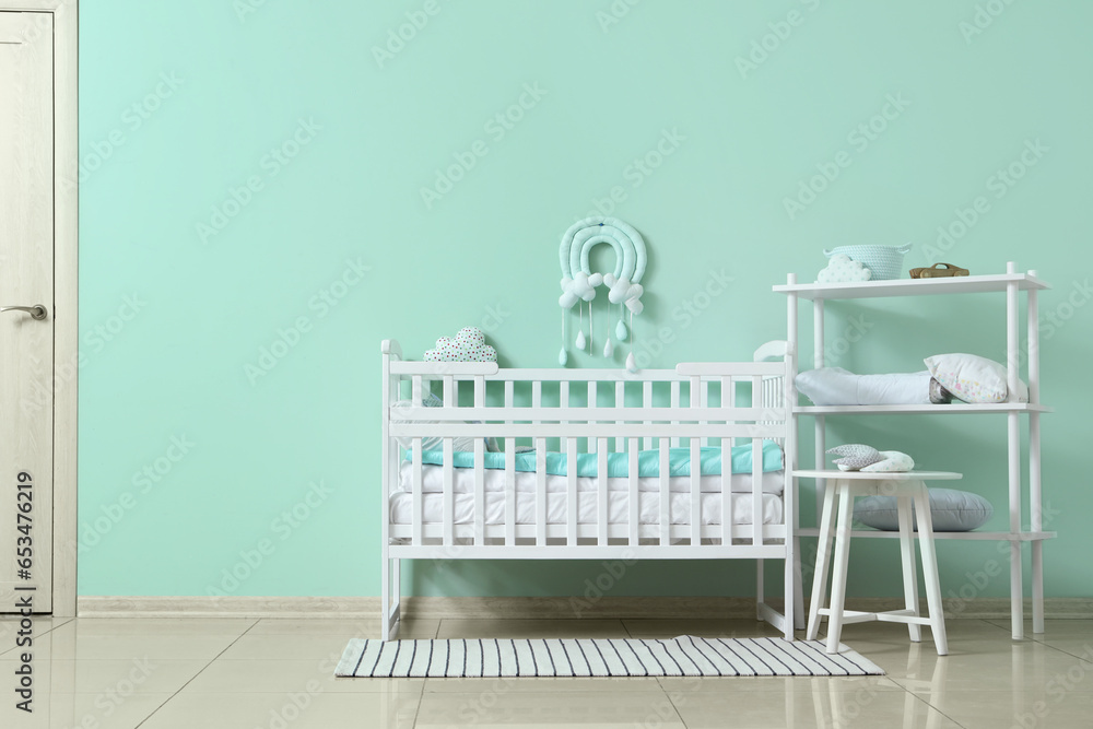 Interior of childrens room with crib near turquoise wall