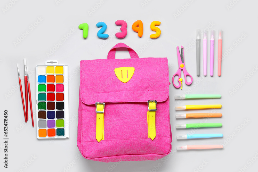 Stylish school backpack with different stationery on grey background