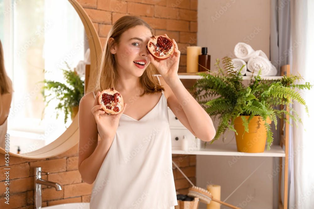 Young woman with pomegranate and under-eye patches in bathroom