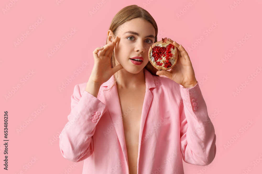 Young woman with pomegranate on pink background