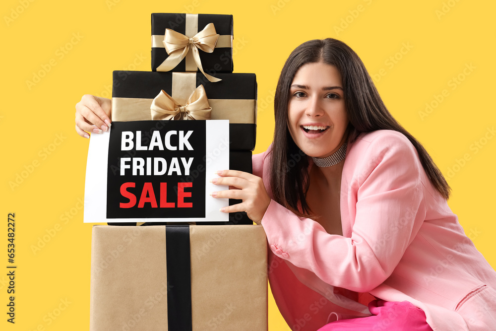 Young woman with gift boxes on yellow background. Black Friday sale