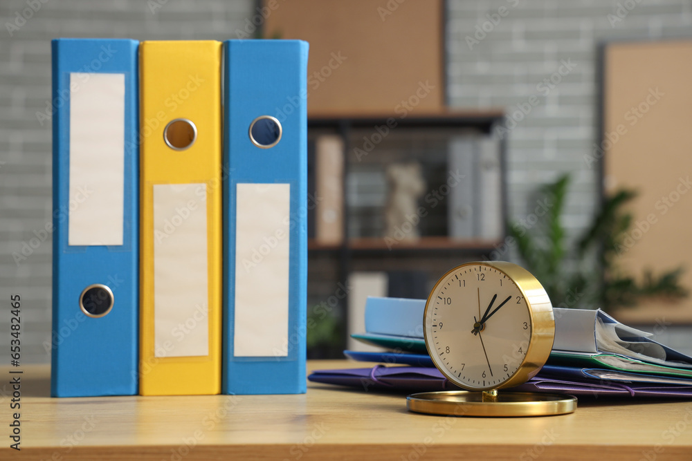 Document folders with alarm clock on desk in office, closeup