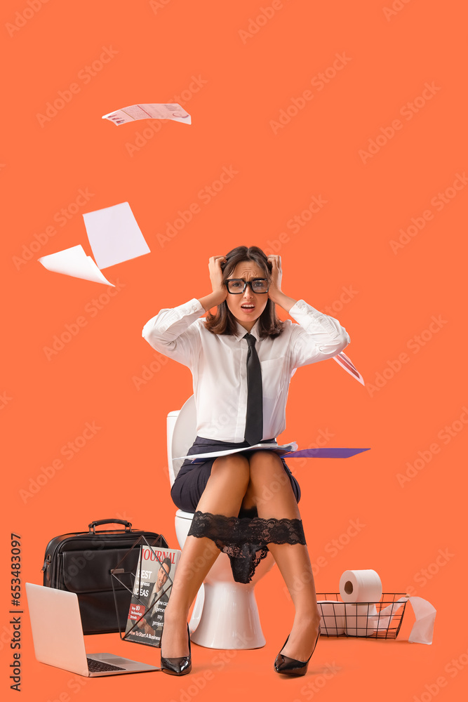 Stressed young businesswoman sitting on toilet bowl against orange background