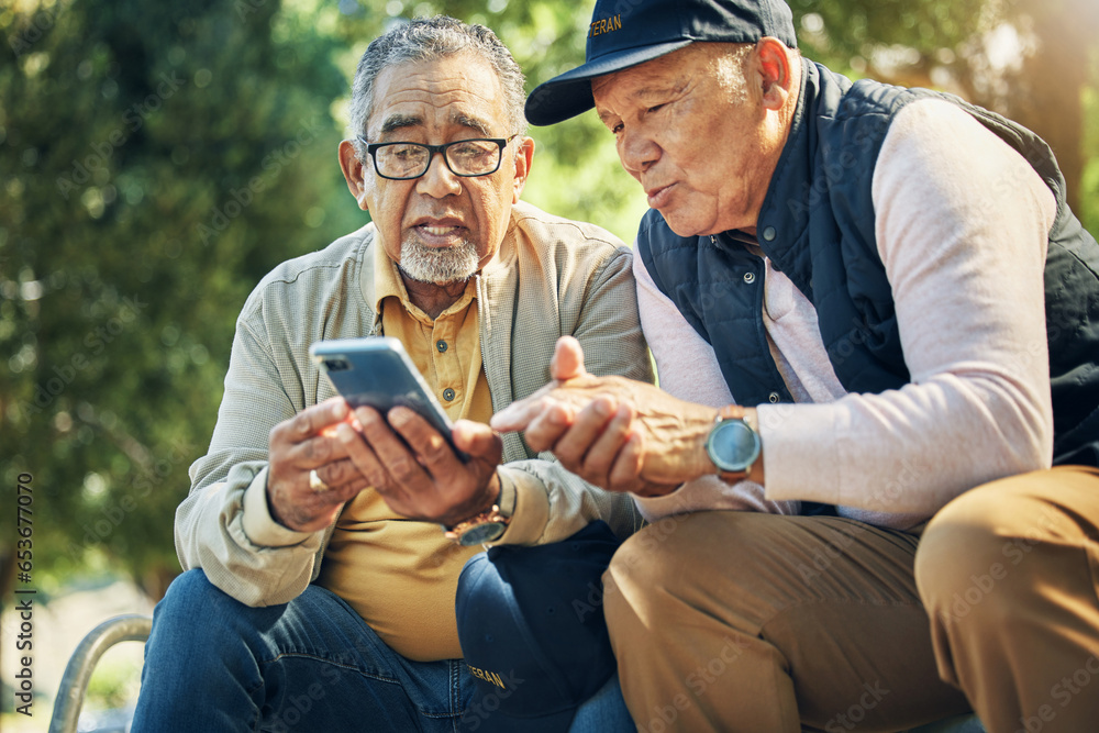 Senior men, friends and phone in park, reading and talk with memory, thinking and relax in sunshine. Elderly people, smartphone and talking on bench, nostalgia and check social media notification