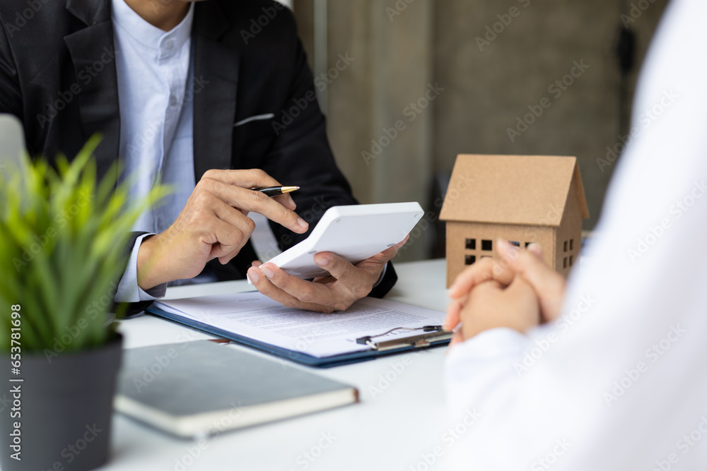 Businessman, real estate agent discussing the terms of the house purchase agreement contract document and letting the client sign legally, mortgage, rent, insurance.