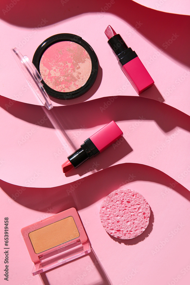 Composition with cosmetic products and makeup sponge on pink background