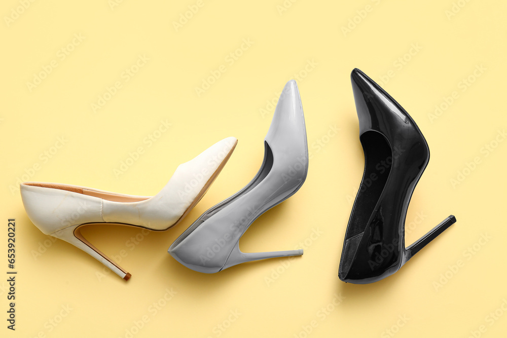 Stylish high heeled shoes on color background, top view