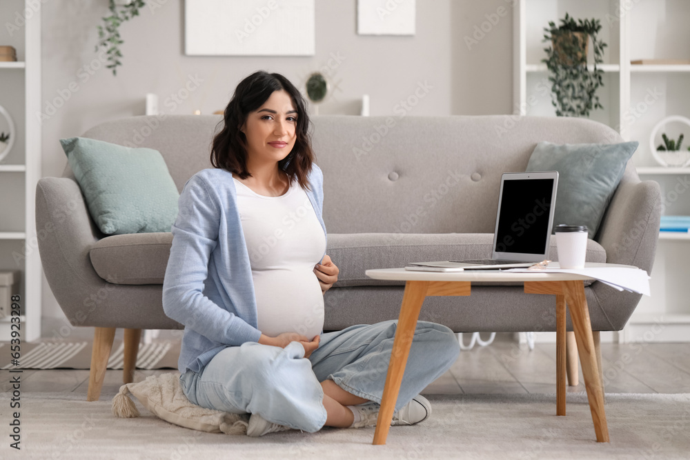 Young pregnant woman working with laptop at home