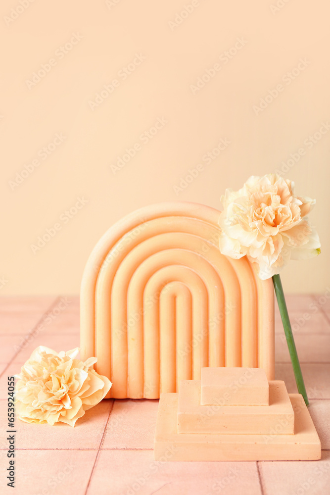 Decorative plaster podiums with daffodils on tile against pale orange wall