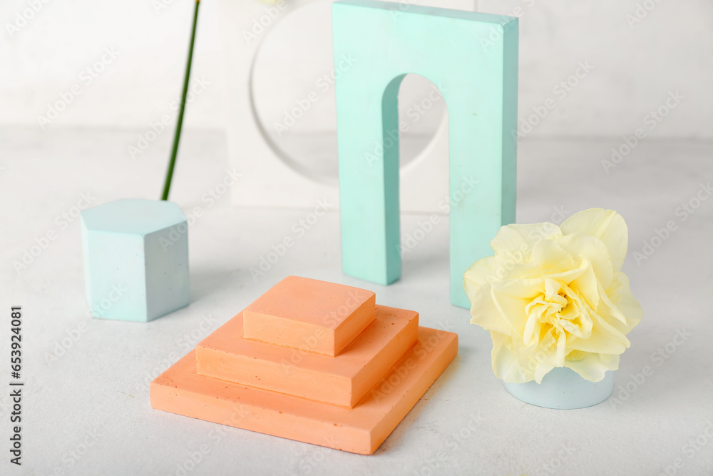 Decorative plaster podiums with daffodils on table against white wall