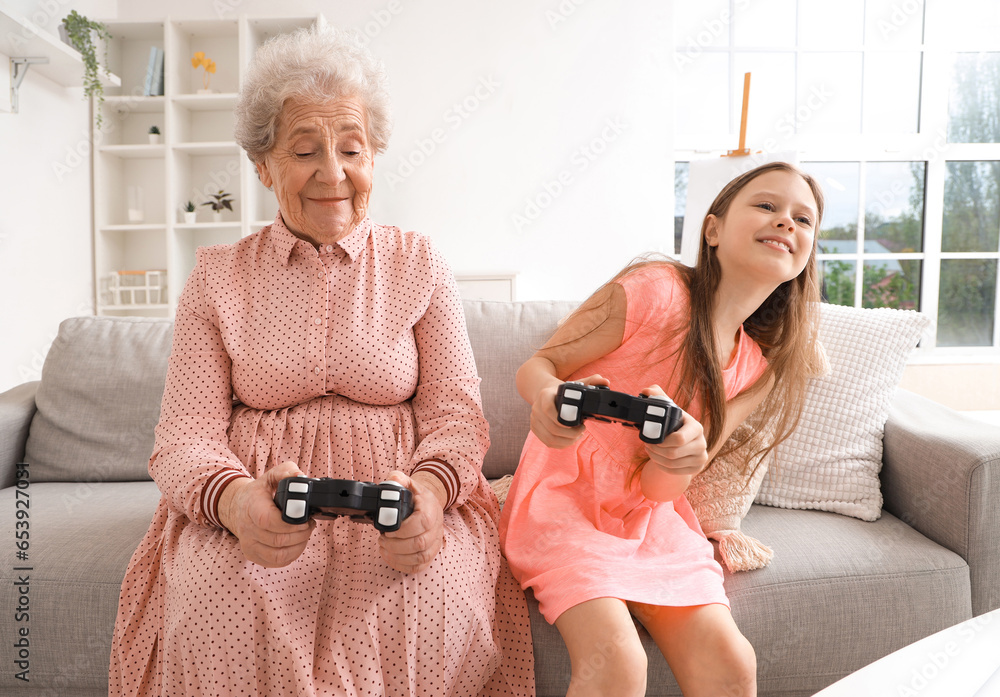 Little girl with her grandmother playing video game at home