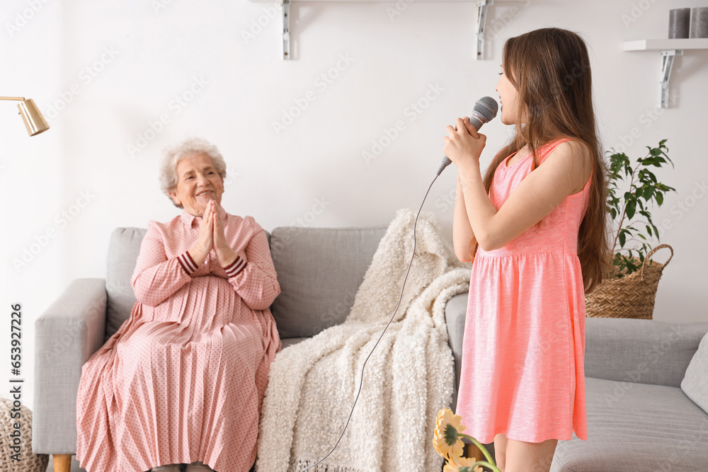 Senior woman and her little granddaughter singing at home