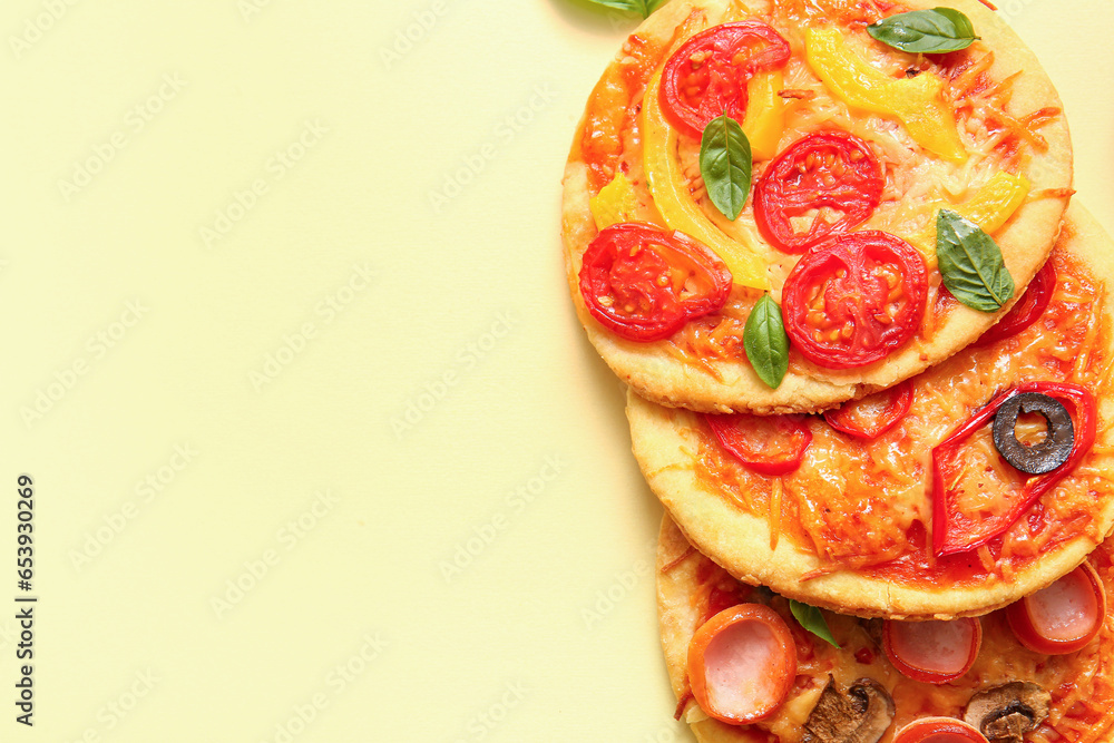 Different tasty mini pizzas on yellow background