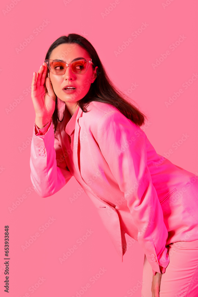 Young woman in stylish suit on pink background