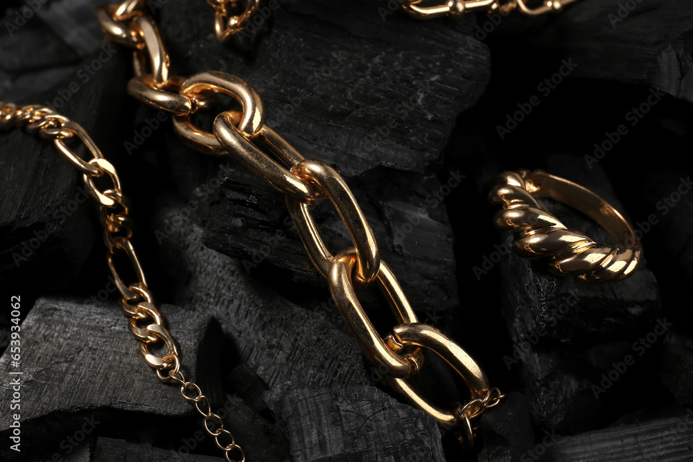 Beautiful chain bracelets and ring on black charcoal, closeup