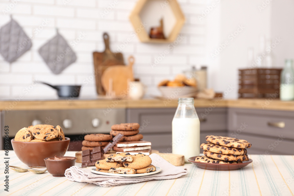 Cookies with chocolate and bottle of milk on table in kitchen