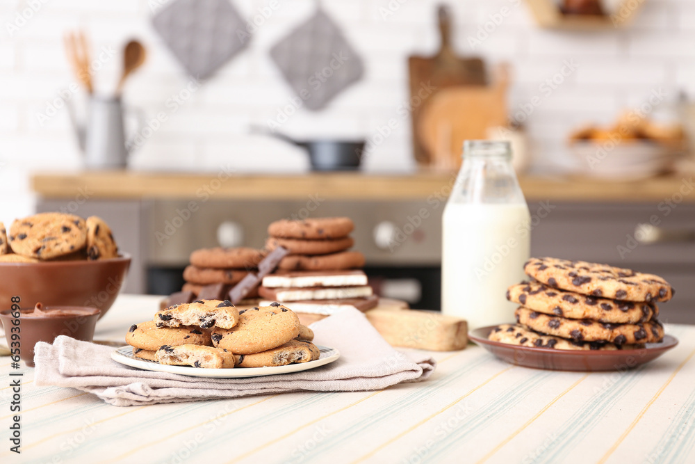 Cookies with chocolate and bottle of milk on table in kitchen