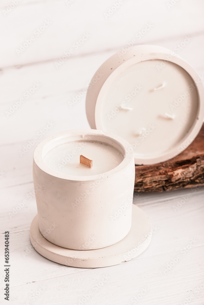 Holders with candles and tree bark on white wooden background