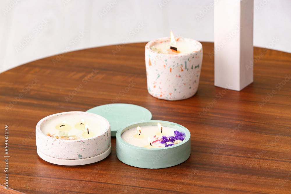 Holders with burning candles on table in room, closeup