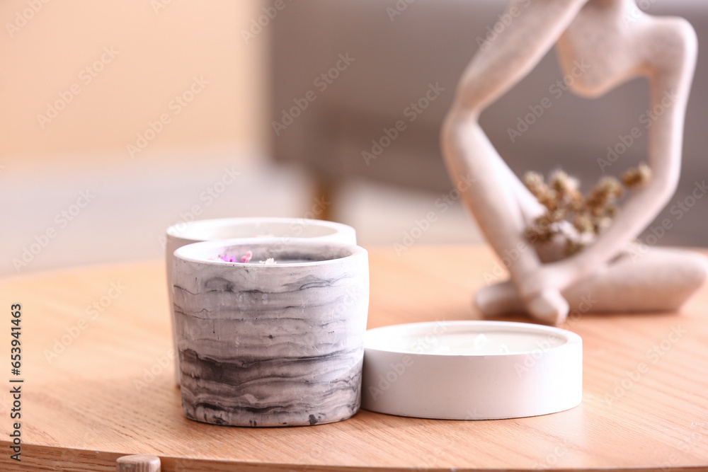 Holders with candles and decor on table in room, closeup