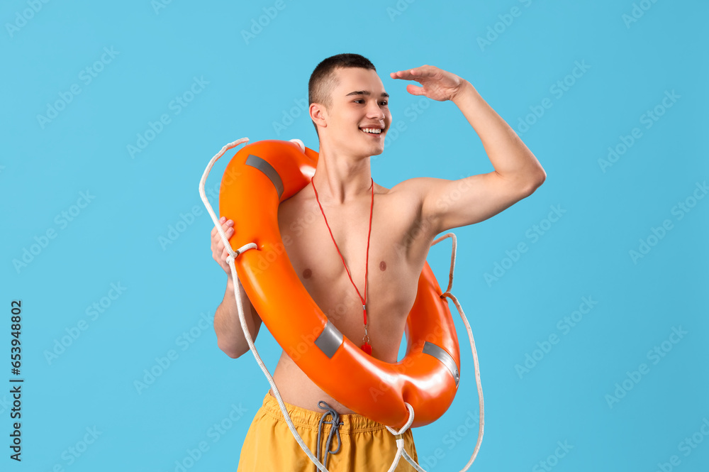 Male lifeguard with ring buoy on blue background