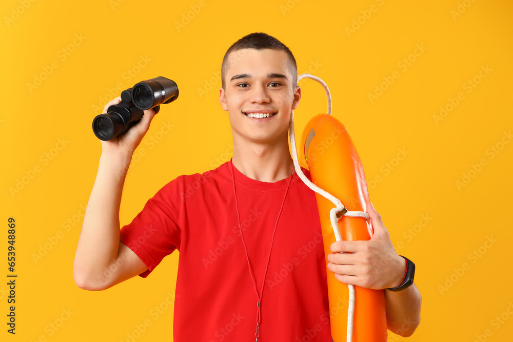 Male lifeguard with binoculars and ring buoy on yellow background