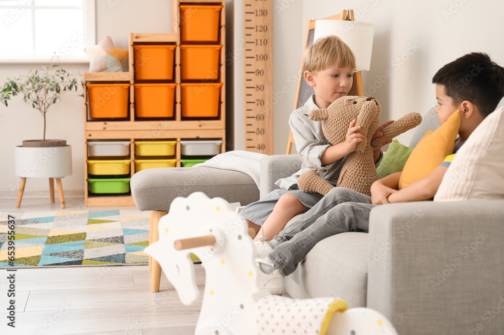 Cute little boys playing with toy bear at home