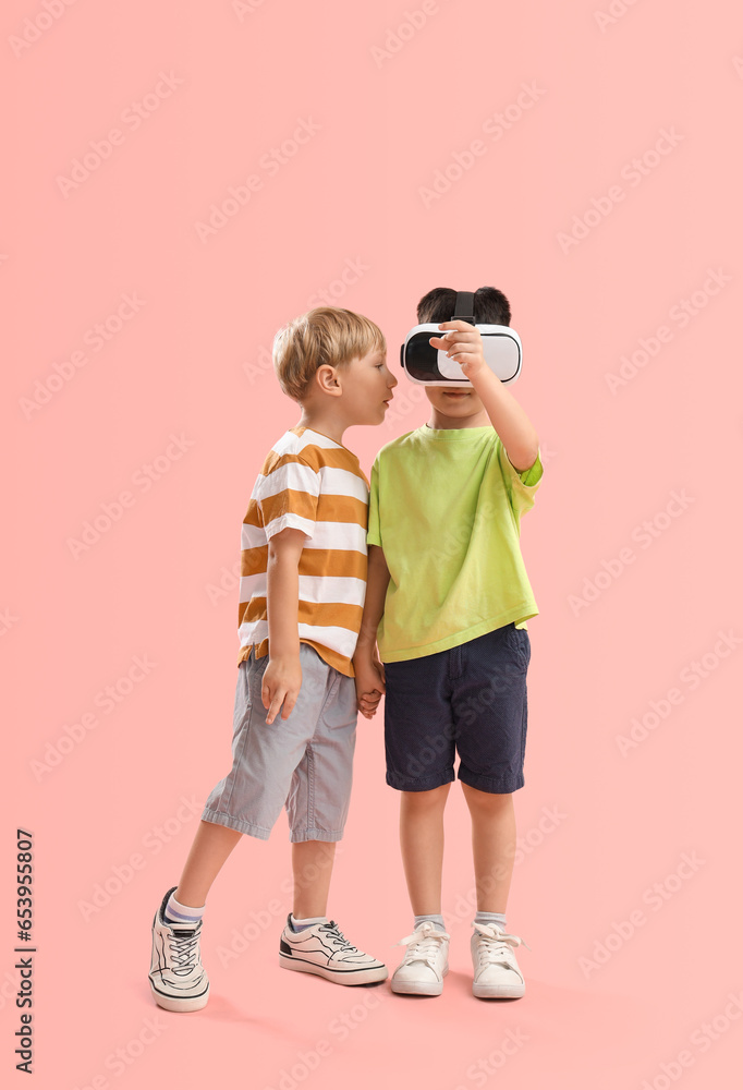 Cute little boys with VR glasses on pink background