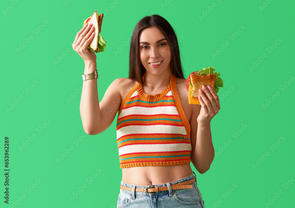 Young woman with tasty sandwiches on green background