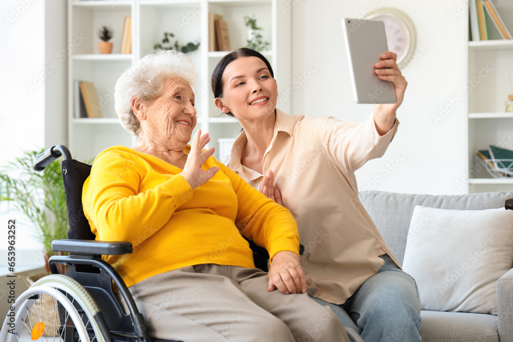 Senior woman in wheelchair with her daughter video chatting at home