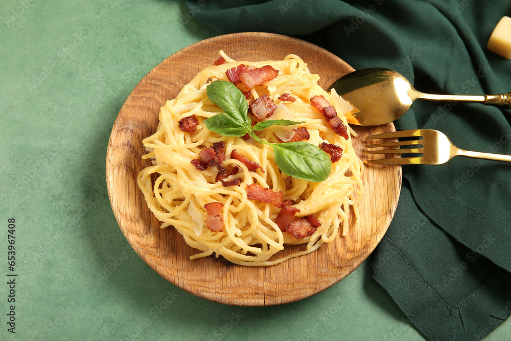 Plate with tasty pasta carbonara on green background